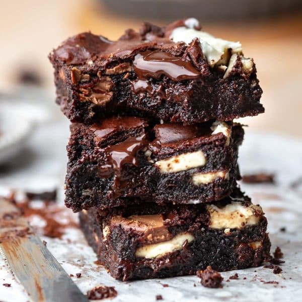 Stack of fudgy batchr. brownies drizzled with warm chocolate